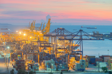 Container Cargo freight ship with working crane bridge in shipyard at dusk for Logistic Import Export background.