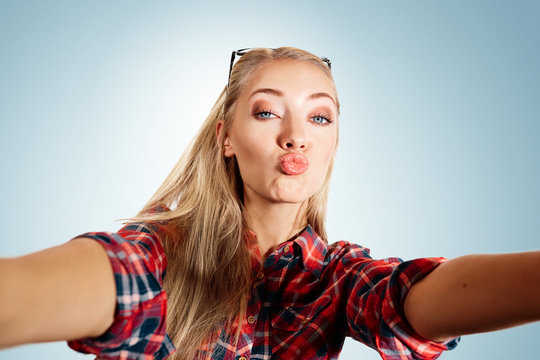 Close up portrait of a young kissing blonde girl holding a smart