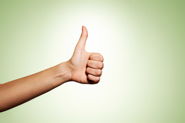 Woman hand with thumb up isolated on green background. Good sign