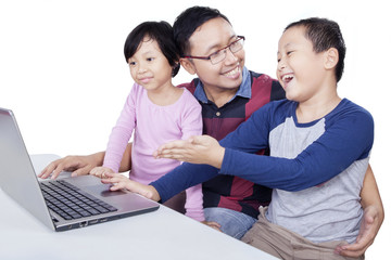 Excited kids using laptop with dad