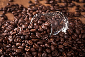 some coffee bean in glass of coffee bean heap on the wood table