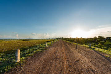 Fototapeta na wymiar Rural dusty countryside road with sunset