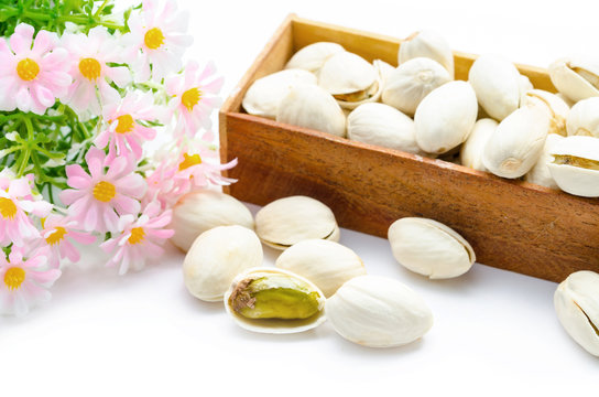 Pistachio nuts in wooden box with flower.