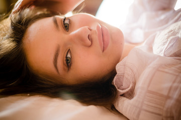 closeup portrait of beautiful tender young woman in bed looking