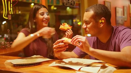 A young couple eating at a downtown pizzeria