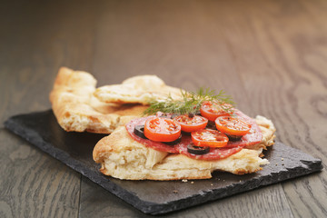 sandwich with pita bread salami and vegetables on wood table
