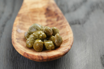 marinated capers in wood spoon on table