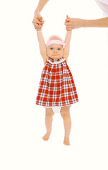 Little child hanging on mom's hands and having fun