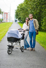 happy man and woman walking with baby pram outdoors