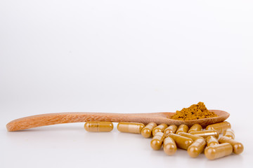 herbal capsules on wooden spoon isolated on white backgroun