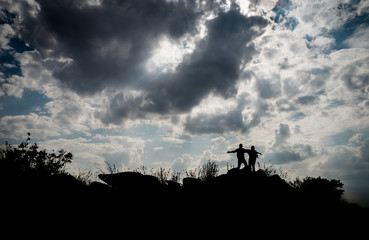 Obraz na płótnie Canvas Silhouetted couple standing on top of a cliff