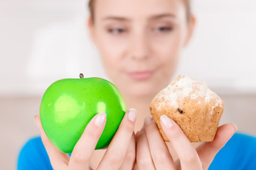 Nice girl holding apple and muffin 