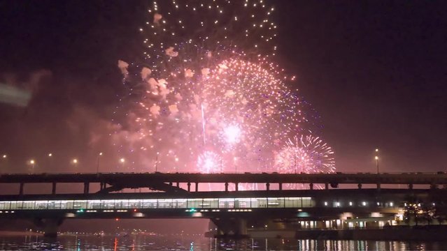 Colorful fireworks reflect from water,  beautiful bridge scenery