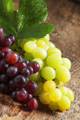 Green and purple round  grapes on old  wooden table, selective f