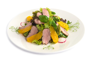 green salad with duck fillet orange and red radish on the white plate