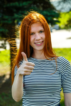 red-haired girl with freckles showing a thumbs up and smiling