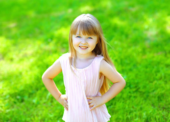 Naklejka na ściany i meble Portrait of happy smiling child little girl on the grass in summ