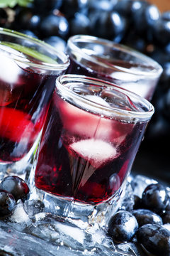 Cold dark grape juice with ice, selective focus
