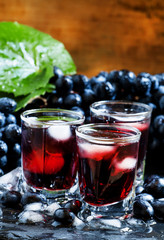 Cold dark grape juice with ice, selective focus