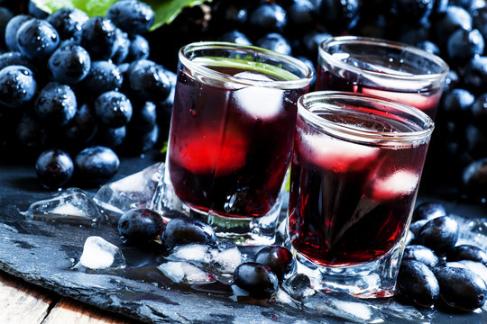 Cold dark grape juice with ice, selective focus