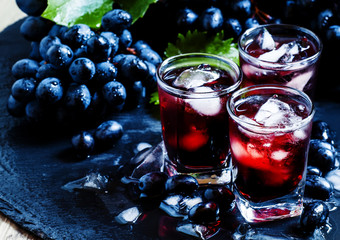 Cold dark grape juice with ice, selective focus