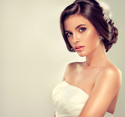Girl model in a white wedding dress with elegant hairstyle 
