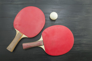 Two red table tennis rackets on dark background