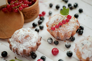 Shot of english muffin blueberry and red or black currant and sugar. Image of muffins on white board wood background.
