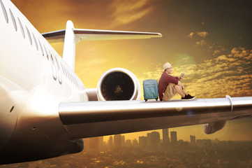 Young tourist sit on the airplane wing