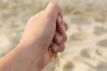 a handful of beach sand in his hand