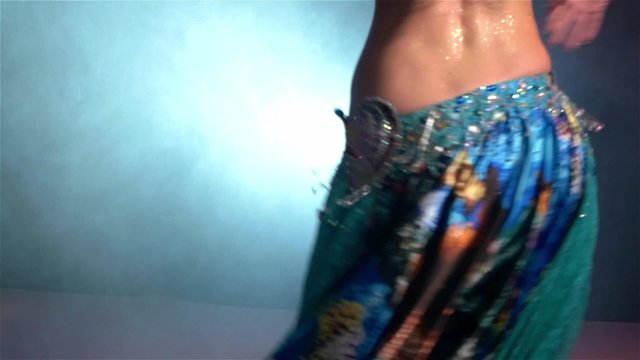 Beautiful young belly dancer in action, slow motion, in smoke