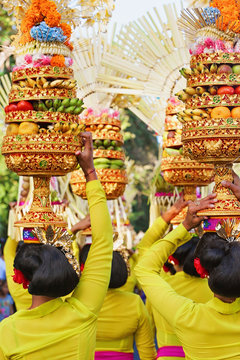 Procession of beautiful Balinese women in traditional costumes carry ritual offerings on heads for Hindu ceremony. Arts festival, culture of Bali people, and Indonesia islands. Asian travel background