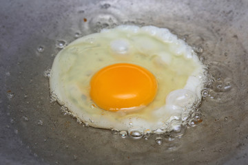 cooking fried egg in hot pan with oil