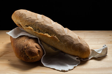 Due pagnotte di pane fatte a mano su un tavolo di legno . Sfondo nero
