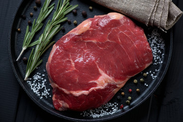 Close-up of raw fresh beefsteak ribeye with seasonings, top view