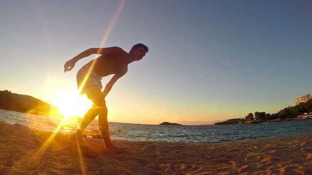 teen doing gymnastics back flip on the sunset beach in slow motion