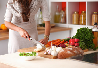 Young woman reading cookbook in the kitchen, looking for recipe