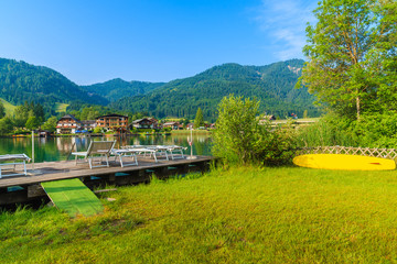 Sunbeds on wooden pier on shore of Weissensee lake in summer landscape of Carinthia land, Austria