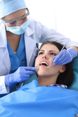 Fototapeta premium Woman dentist working at her patients teeth