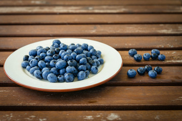 Bilberry on a plate on a wooden table
