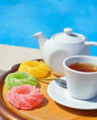 Cup of tea on a sauce, teapot and colored marmalade