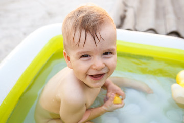 Fototapeta na wymiar child bathes in inflatable pool outdoors, close-up portrait
