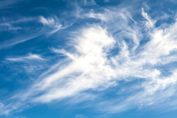White cirrus clouds against a blue sky background
