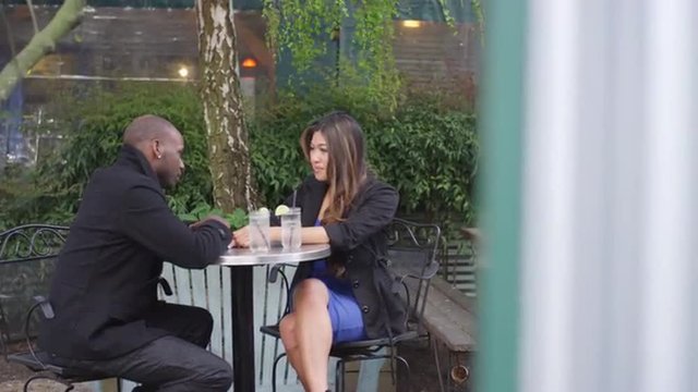 A couple holding hands and talking at an outdoor cafe