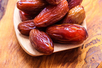 dried dates on spoon wooden background