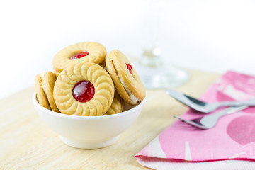Sandwich cookies with cream and strawberry flavoured jam on whit