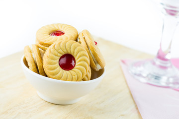 Sandwich cookies with cream and strawberry flavoured jam on whit