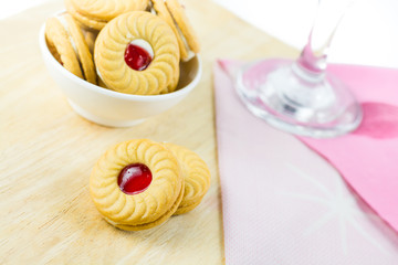 Sandwich cookies with cream and strawberry flavoured jam on whit
