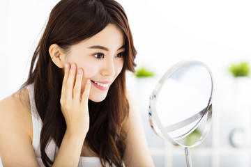 Happy young woman  looking on mirror