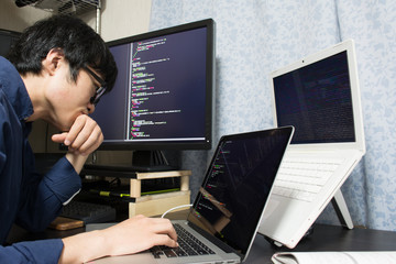 Stressed Asian engineer writing a programme on a computer